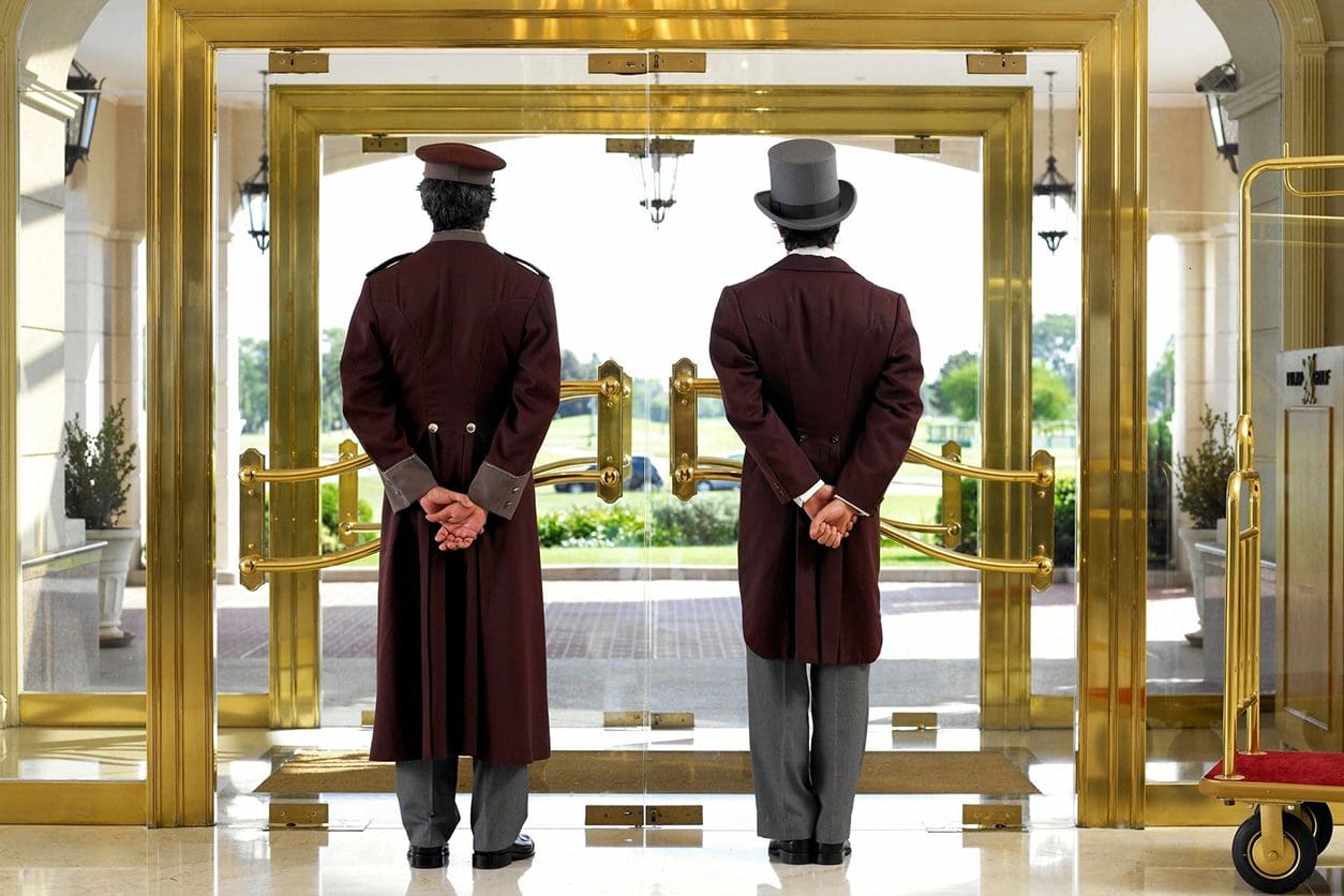 Two men in top hats and suits standing at a door way.