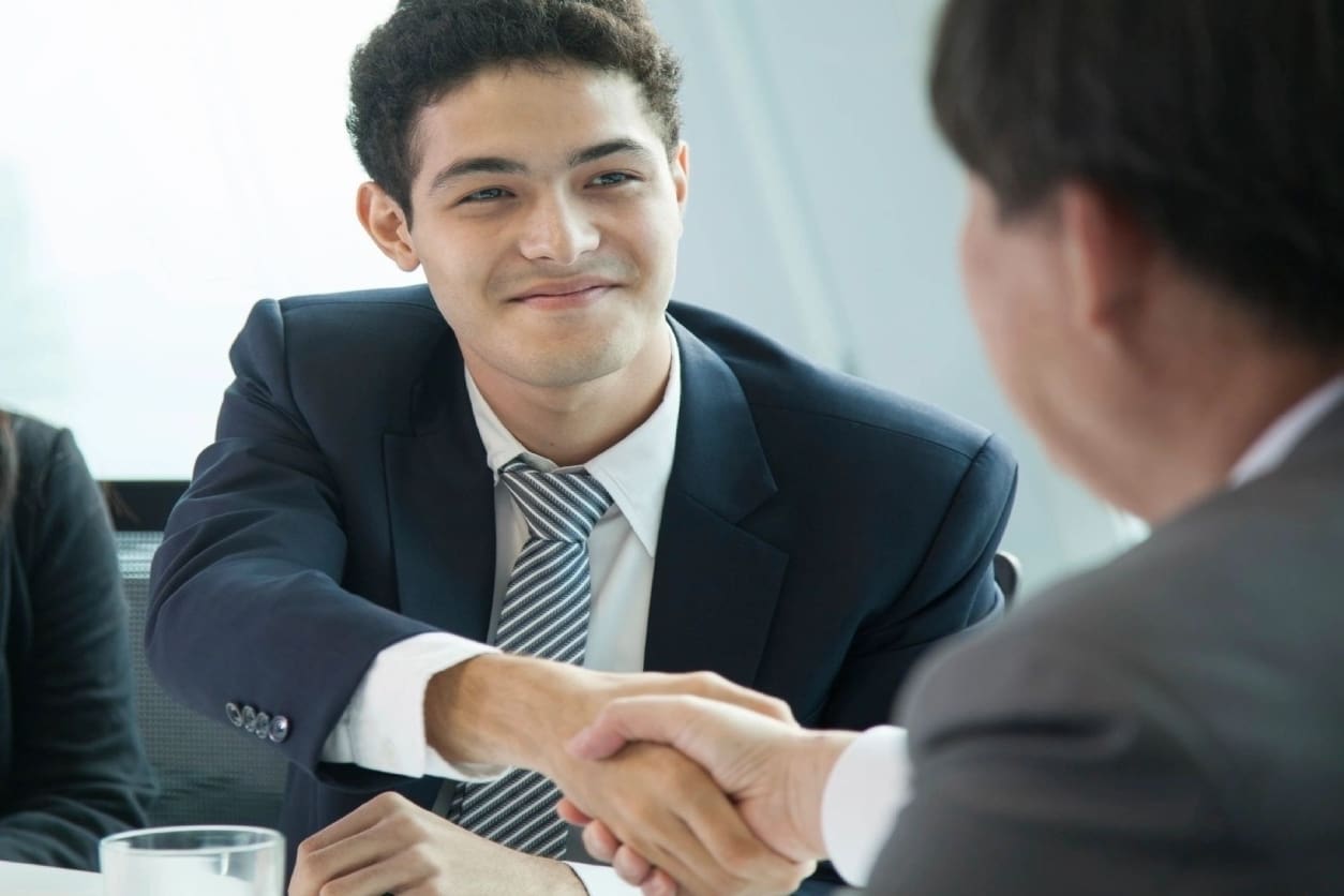 A man in suit shaking hands with another man.